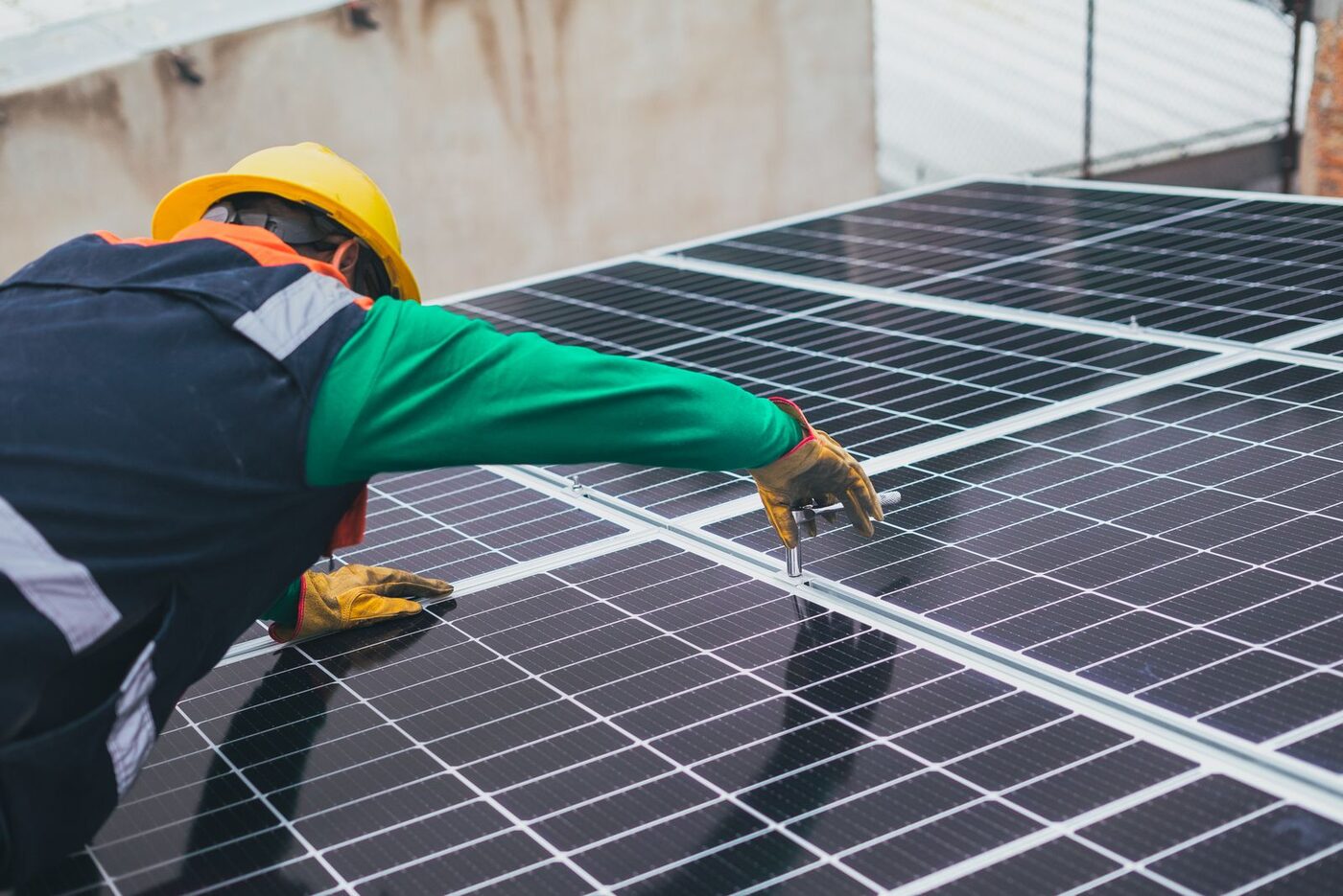 Técnico com capacete fixando módulo fotovoltaico na estrutura do telhado