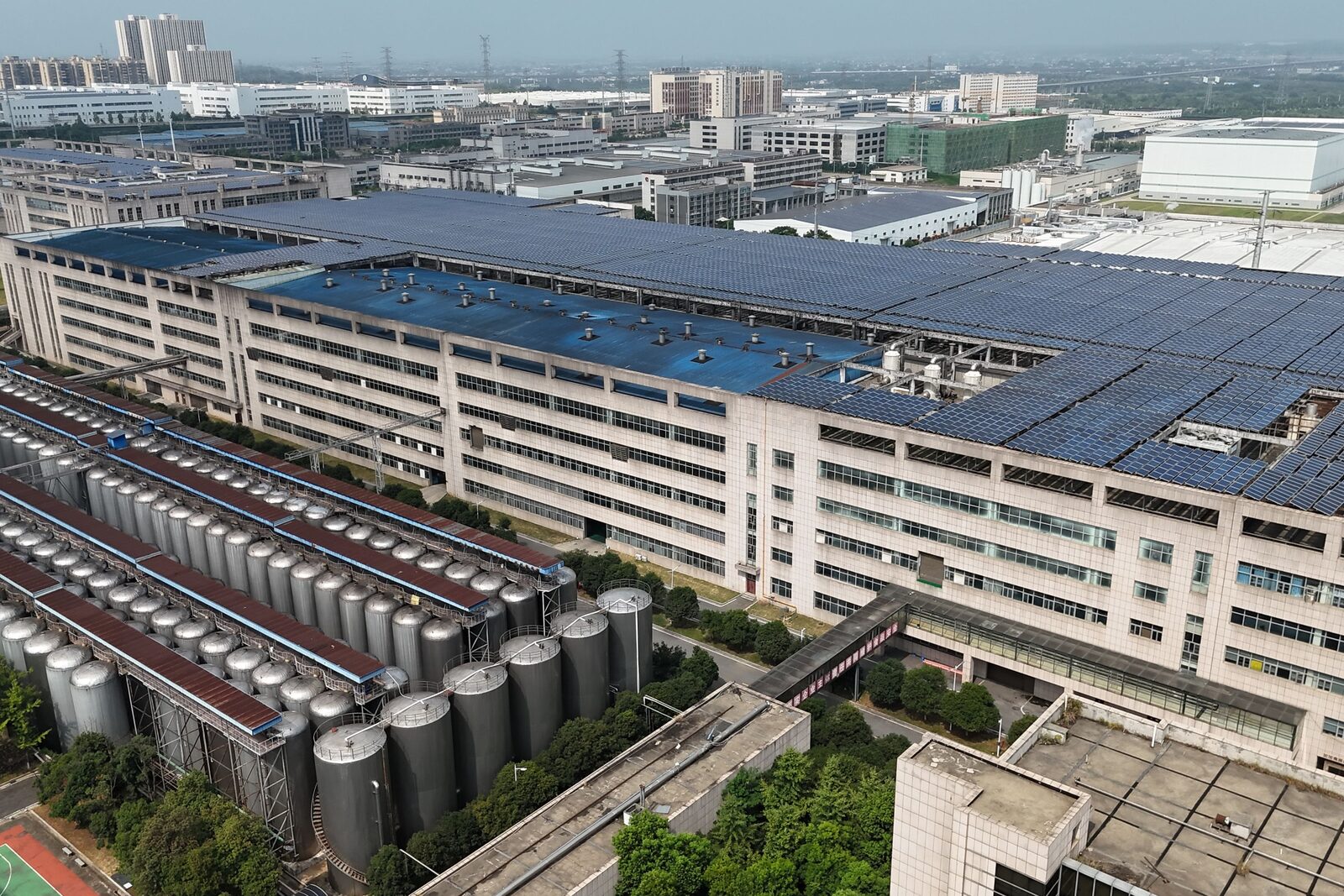Planta industrial com tanques de processo e telhado coberto por painéis solares